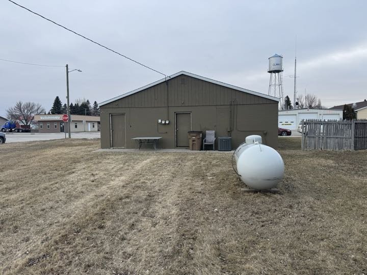 Rear exterior of 116 W Broadway showing cement brick painted exterior, propane tank, and Climax water tower in background